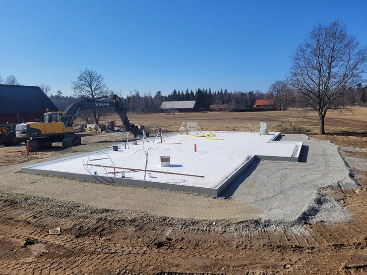 En nyligen gjuten husgrund av Thorssons Entreprenad, omgivet av öppet landskap och blå himmel, som förkroppsligar företagets markentreprenadskapacitet i Halmstad.