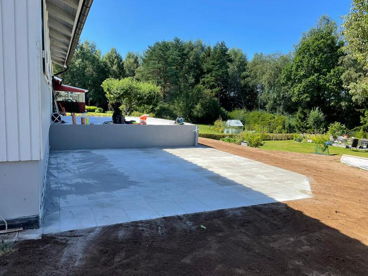 Nyinstallerad ljus stenyta av Thorssons Entreprenad framför ett hus, vilket framhäver deras stenläggningskompetens i Gislaved.